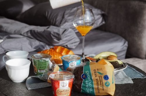 Cozy breakfast setup with croissant, juice, and yogurt on bedside table, creating a relaxing morning vibe.